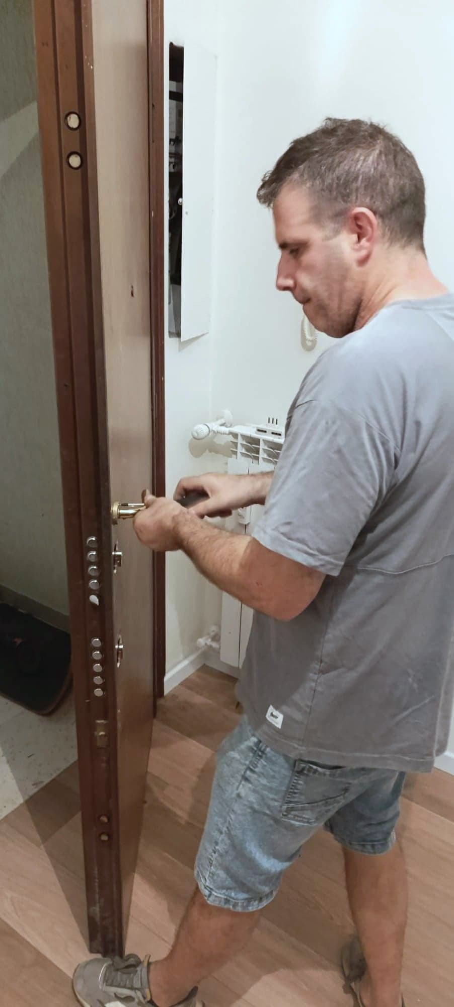 Claudio Cipriani al lavoro sulla serratura di una porta blindata aperta, con la colonna dei catenacci in vista