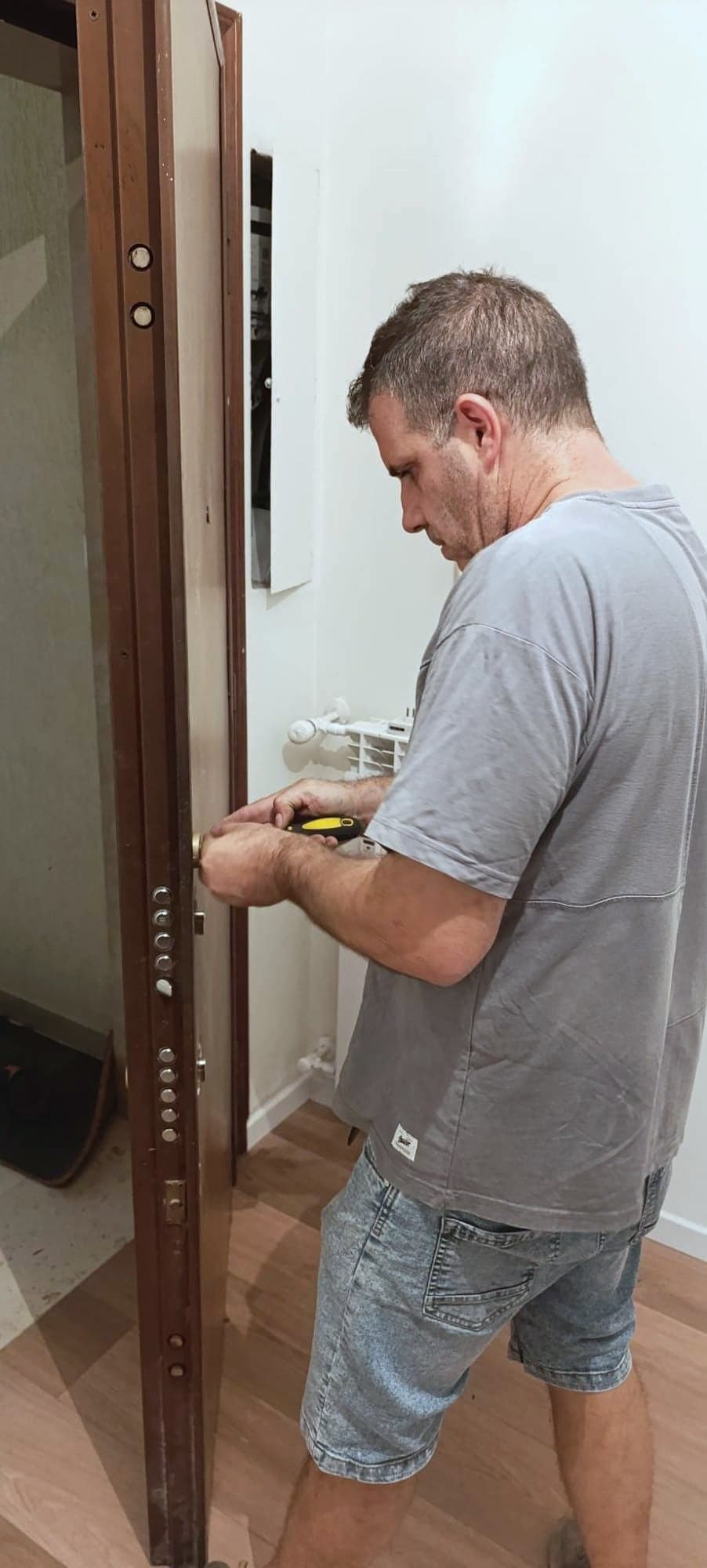 Claudio Cipriani lavora alla serratura di una porta blindata aperta, con i catenacci in vista