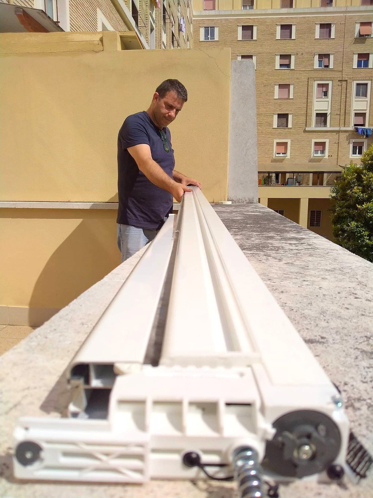 Il controllo di un lungo profilo bianco con il suo meccanismo, sul terrazzo di una palazzina, prima del montaggio